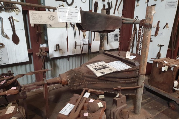 Bellows like these were used in the workshop.  A Blacksmith's leather apron is draped over the bar which was used to operate the bellows